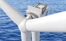 A view from above shows a portion of the top of an offshore wind turbine and blades, all in white with the exception of a circular blue and white GE logo. In the background, blue water runs with waves. 